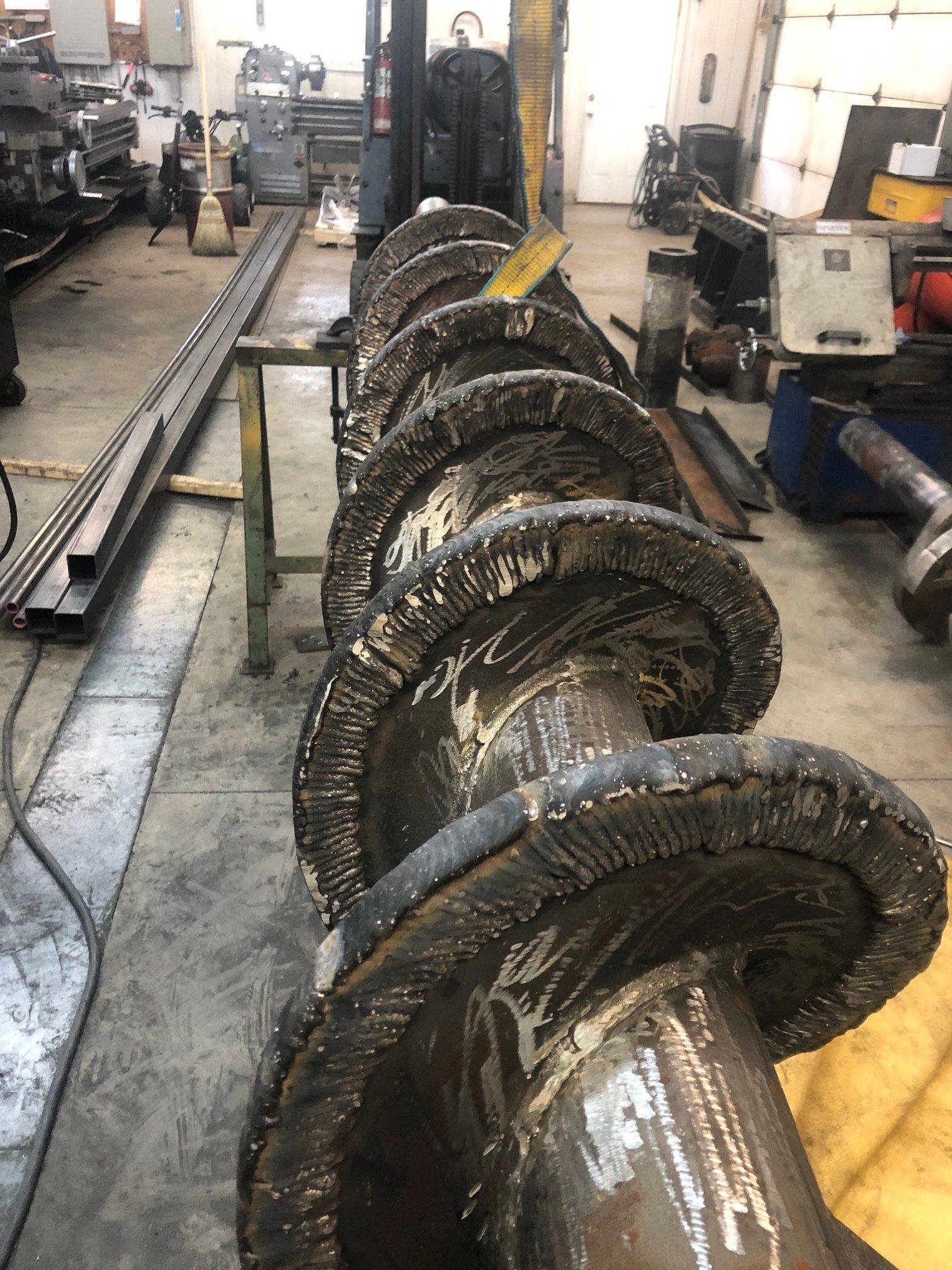 A large metal screw is sitting on a table in a factory.