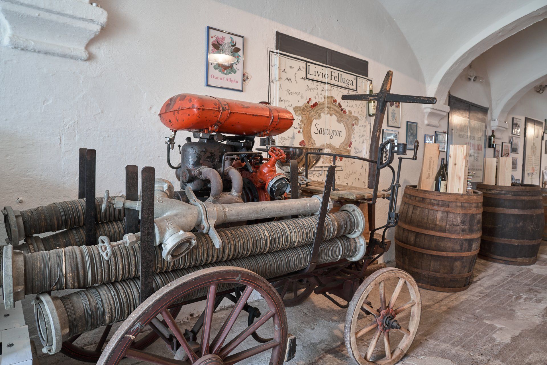 Ein Holzwagen mit Baumstämmen darauf steht in einem Raum mit Fässern.