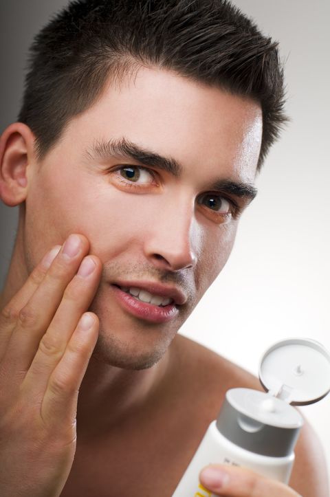 Young handsome man applying creme close up