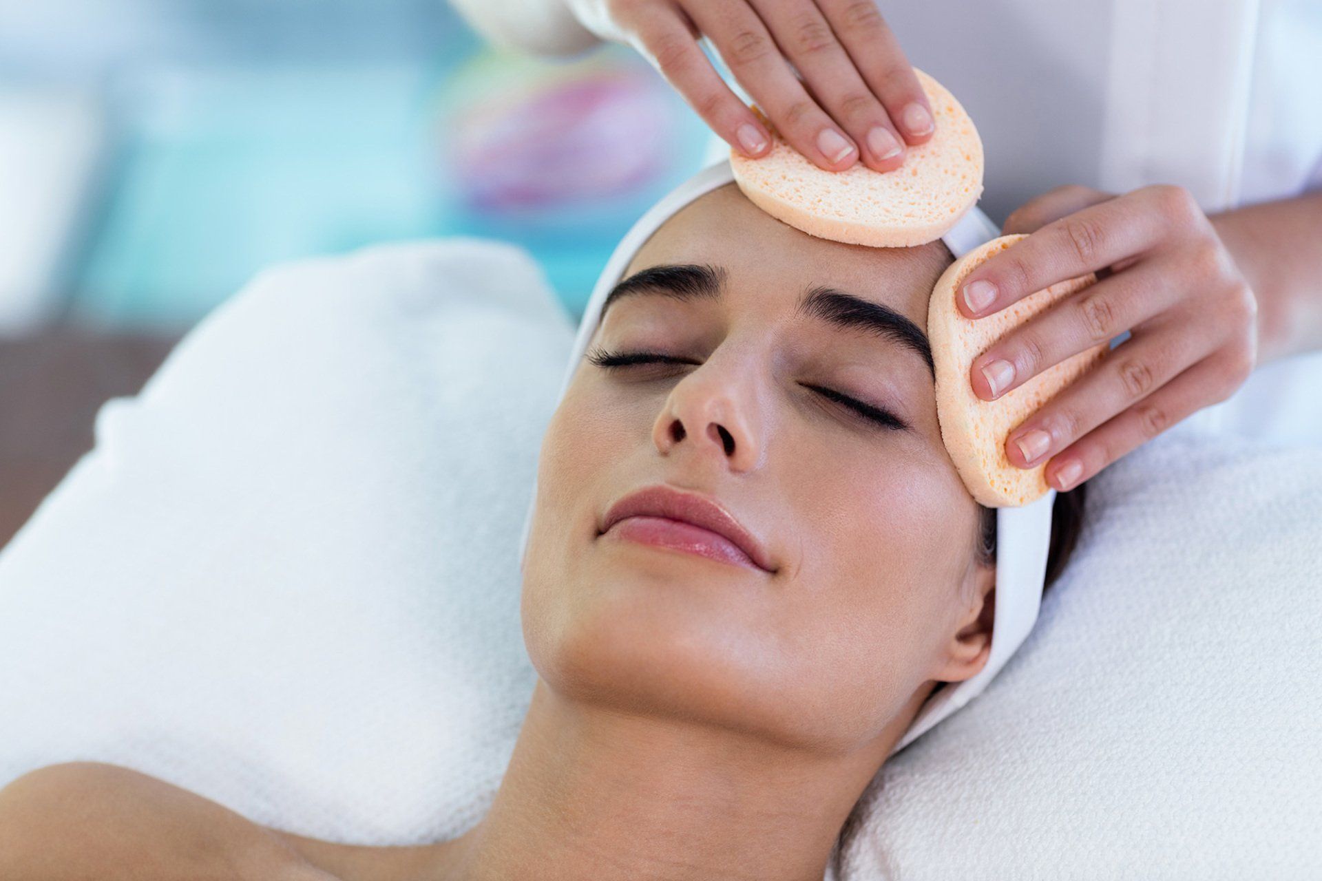 Close up of masseuse cleaning woman face with cotton swabs at spa