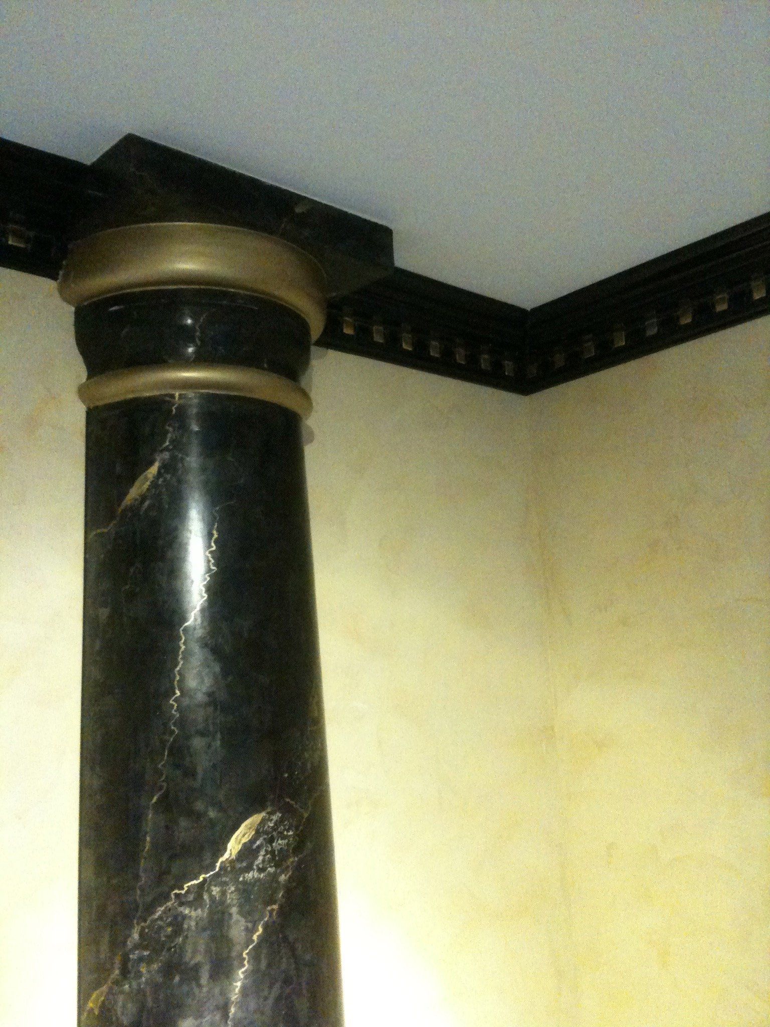 Säule mit schwarz goledener Marmorimitation und gelb gestrichener Wand