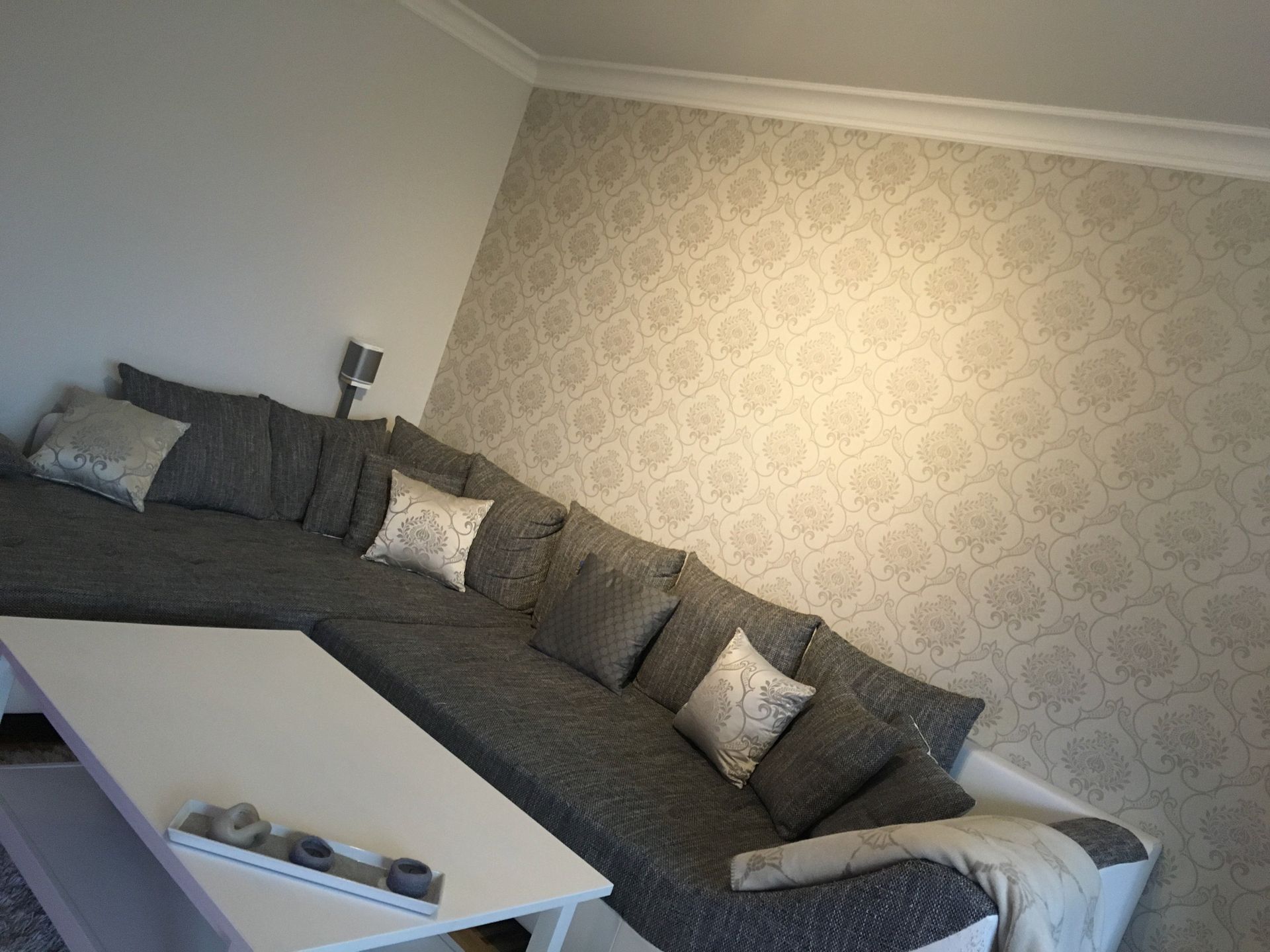 Graues Sofa vor Mustertapete