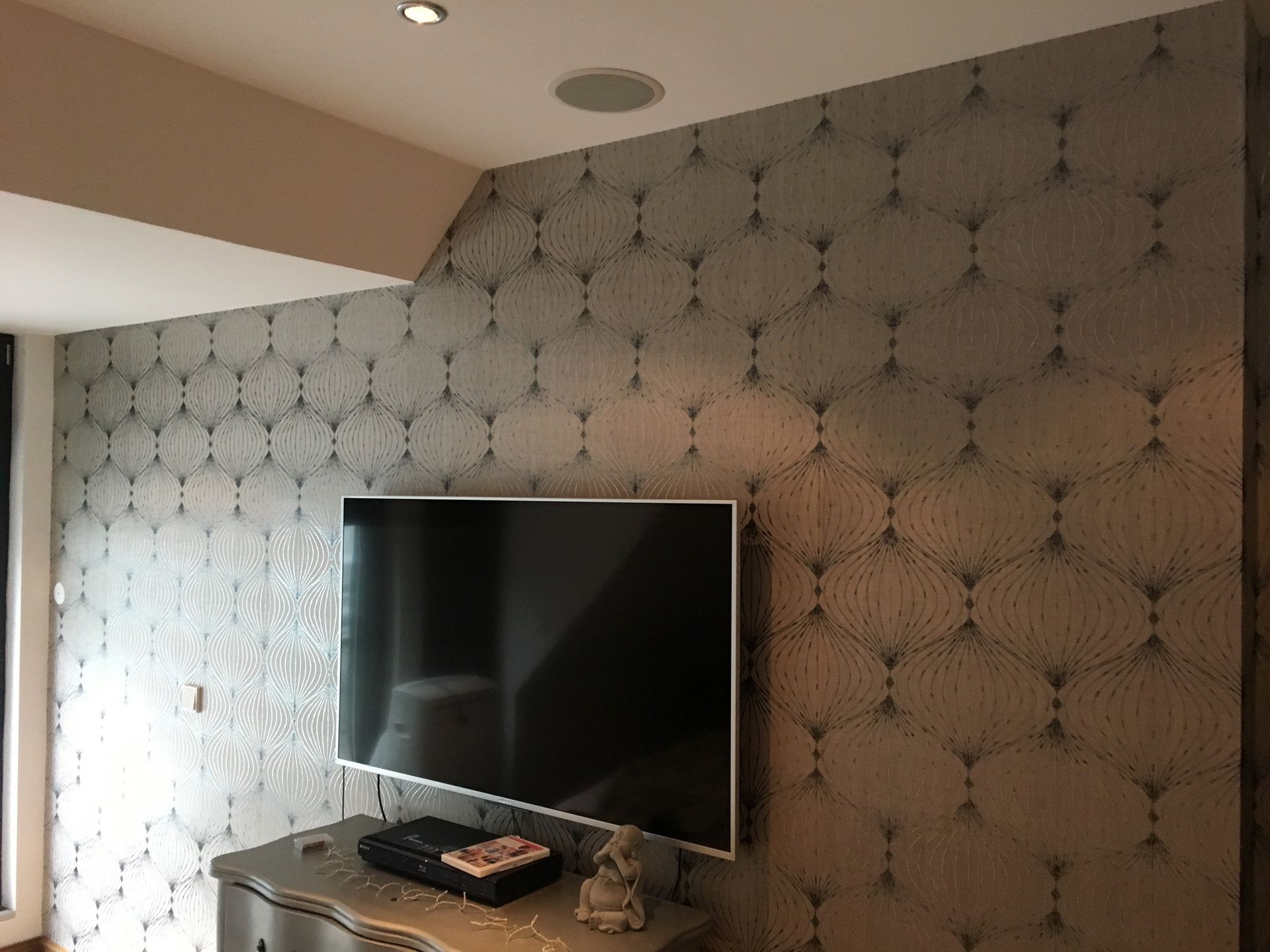 Fernseher vor grauer Mustertapete