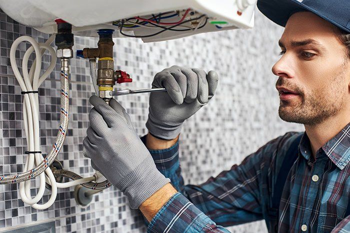 Worker Fixing Electric Broiler — Fresno, CA — Art Douglas Plumbing Inc.