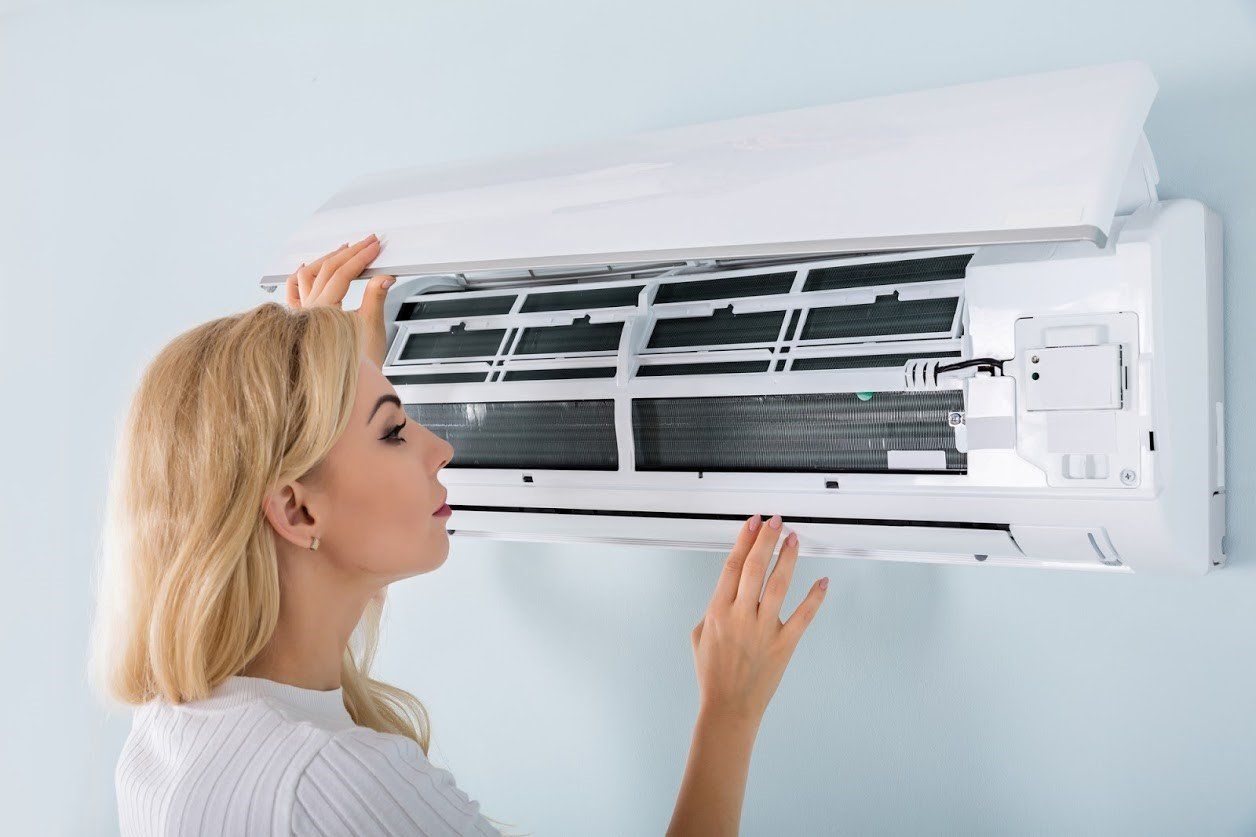 Woman looking to air condition unit — Fresno, CA — Art Douglas Plumbing Inc. Woman looking to air condition unit — Fresno, CA — Art Douglas Plumbing Inc.