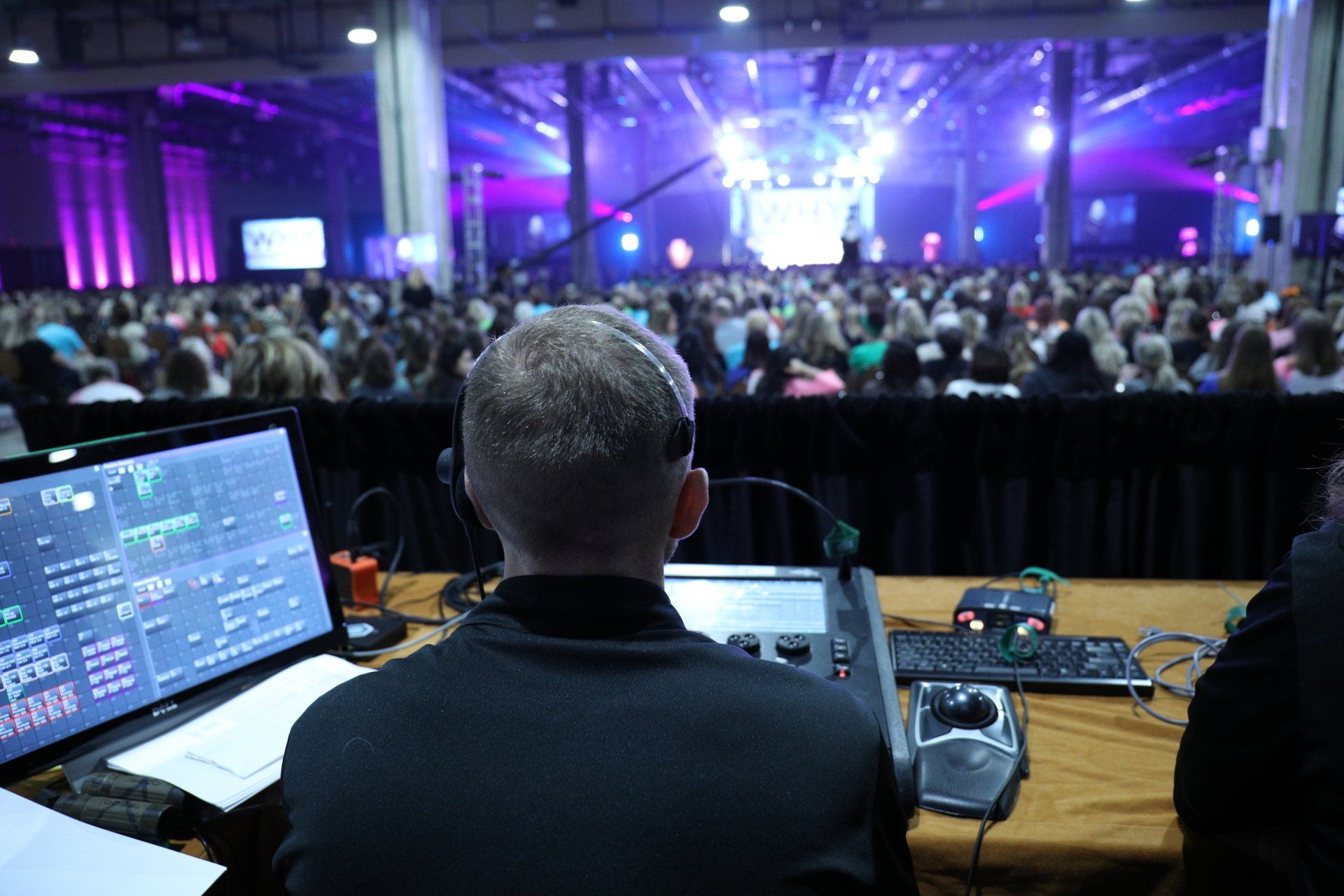 Lighting director managing live show cues from front of house during a corporate conference.