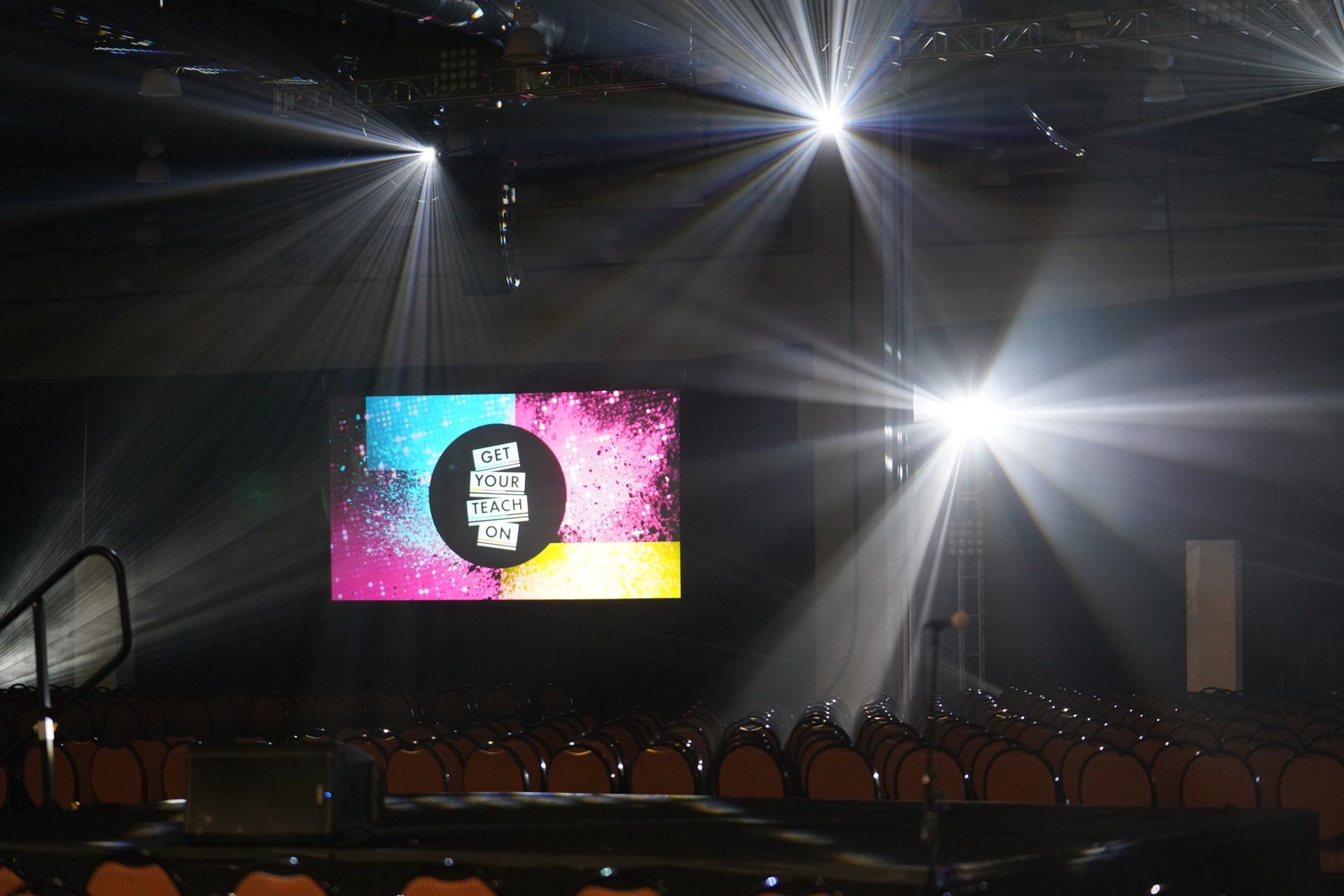 Concert-style stage lighting illuminating a custom LED backdrop before a corporate conference session begins.