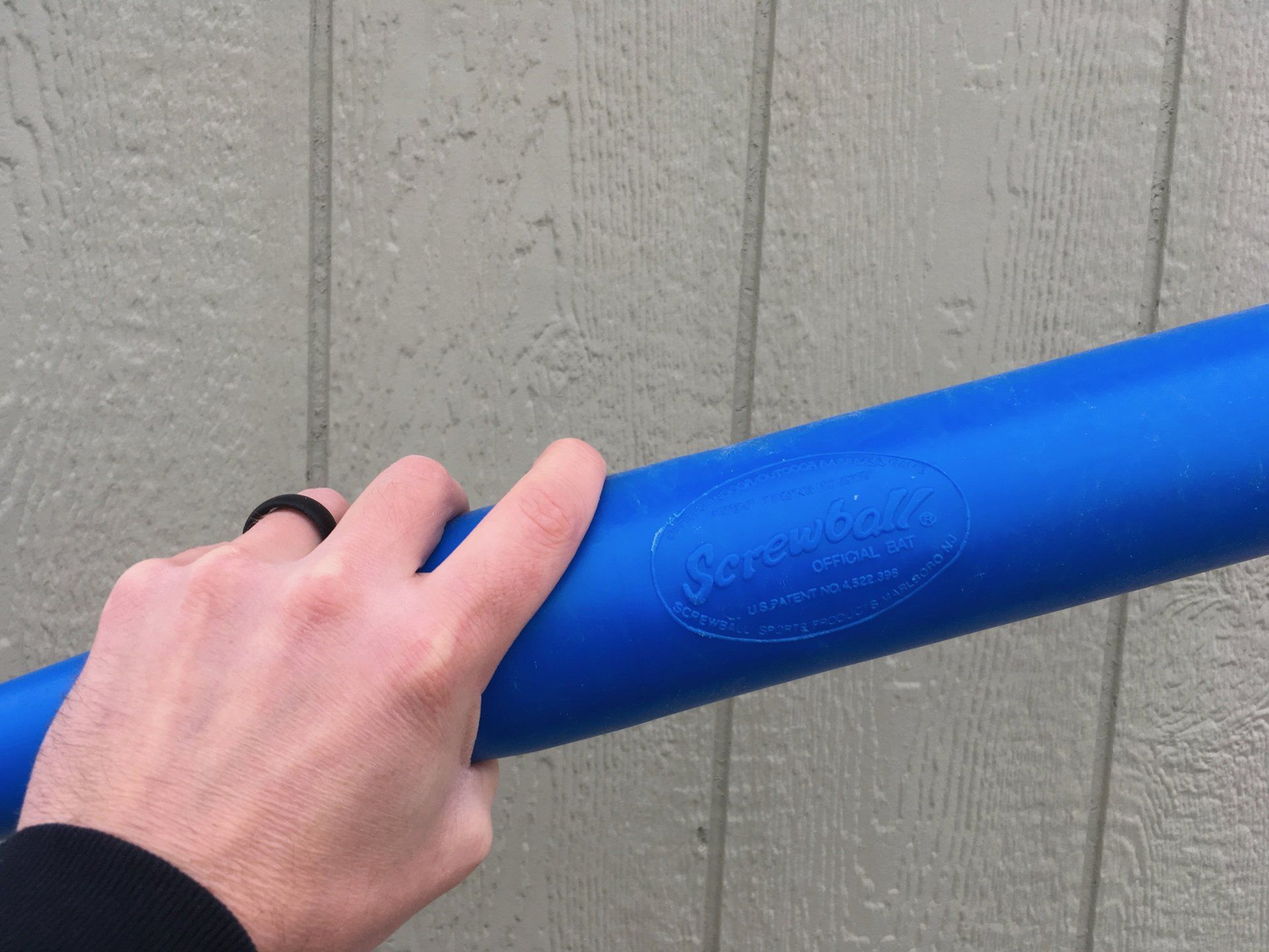 A person is holding a blue baseball bat in their hand.