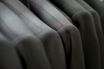 close up of suit coats hanging on a clothing rack
