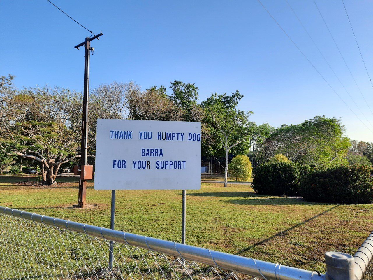 A sign in a grassy field reads, 