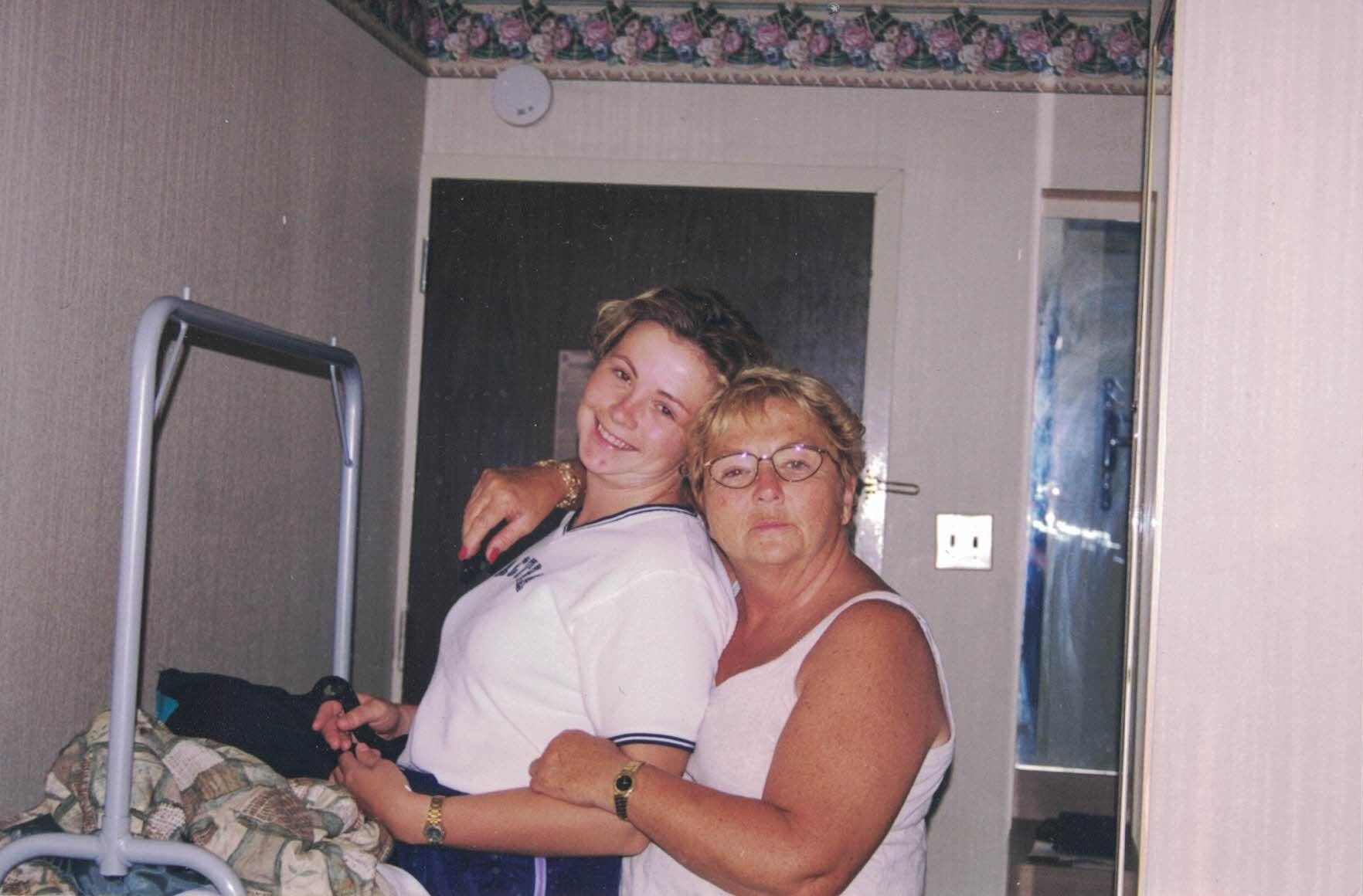 Two women are hugging each other in a bedroom