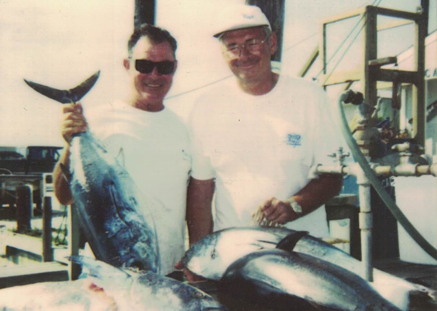 Two men standing next to each other holding a large fish