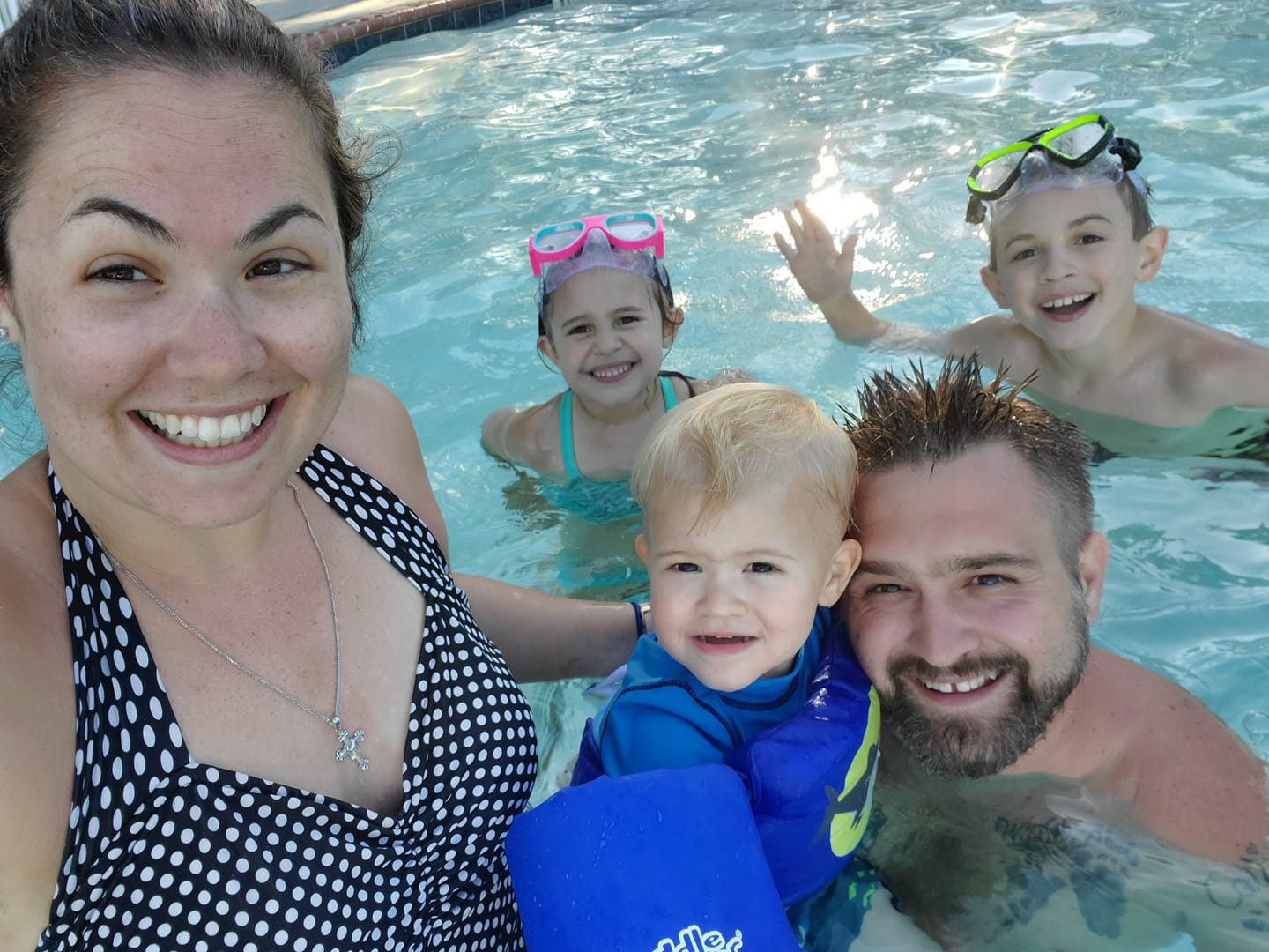 A family is taking a selfie in a swimming pool.
