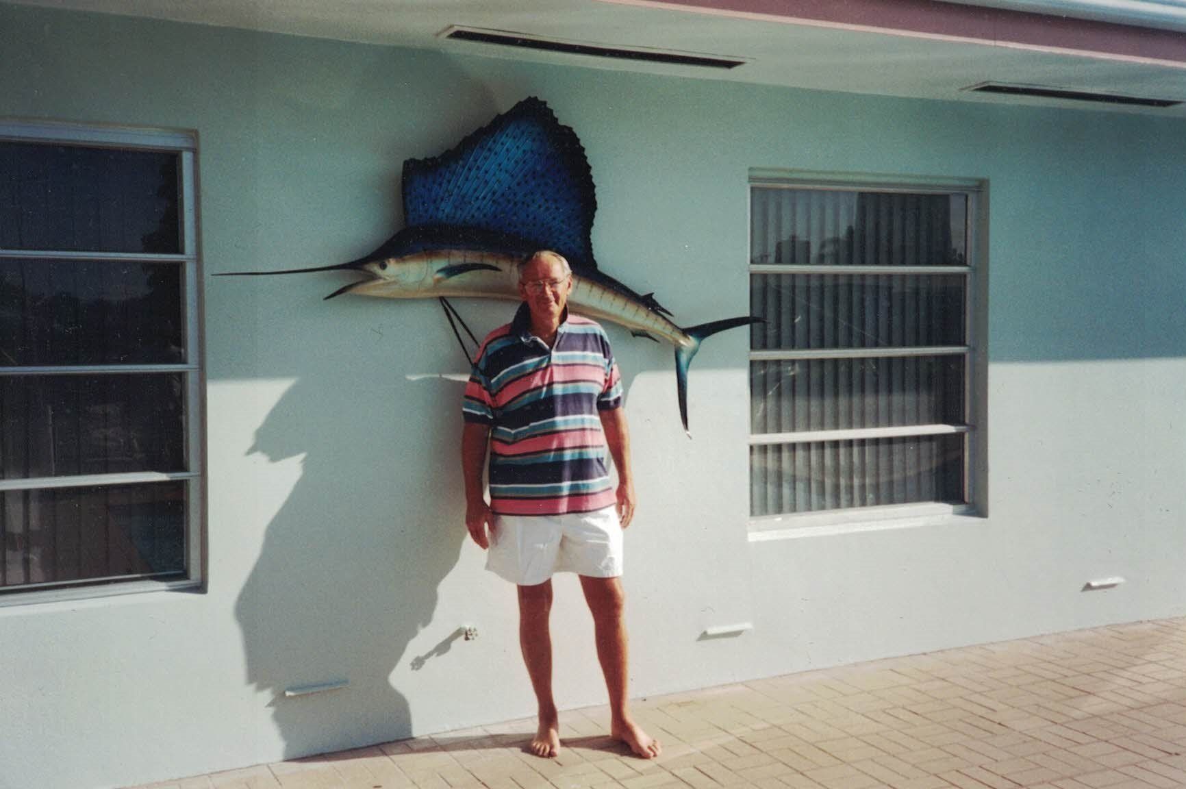 A man standing in front of a sailfish hanging on a wall
