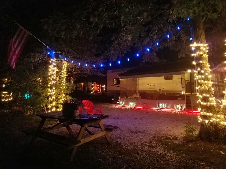 A picnic table is sitting in front of a trailer that is decorated with christmas lights.