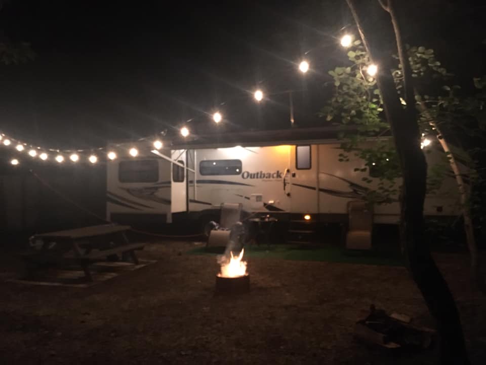 A rv is parked next to a fire pit at night.