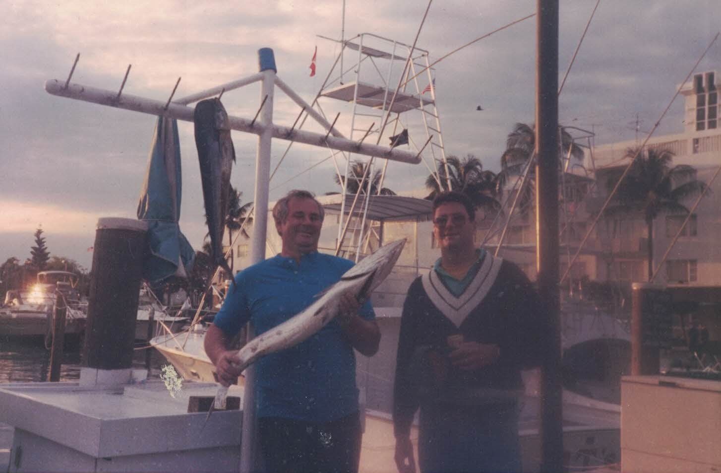 Two men standing next to each other holding a large fish