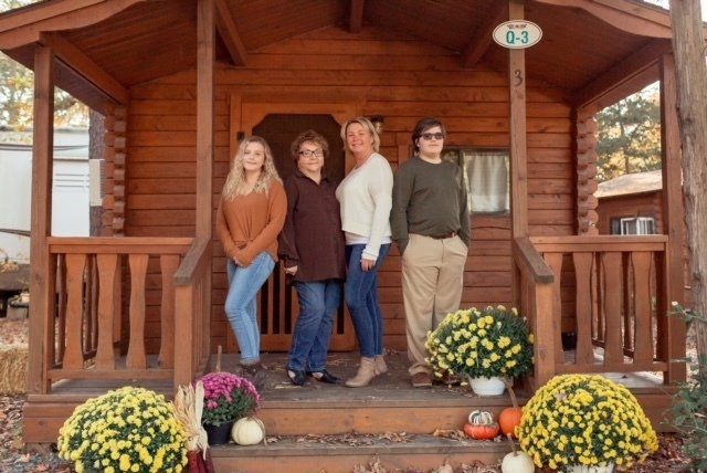 A group of people are standing in front of a wooden cabin.