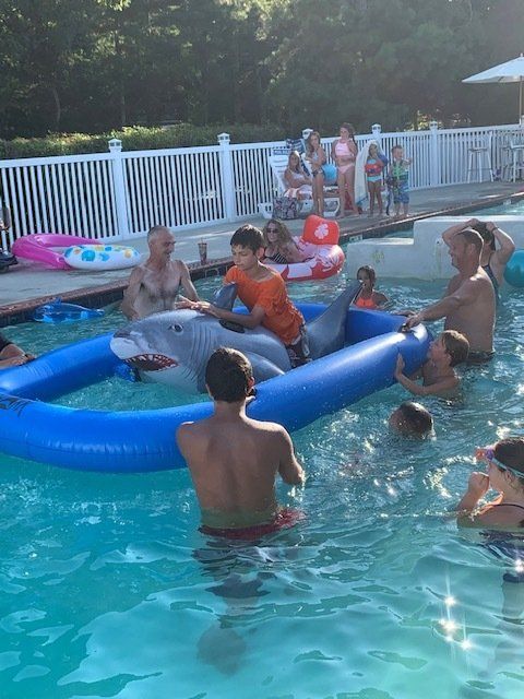 A group of people are playing in a pool with an inflatable dolphin