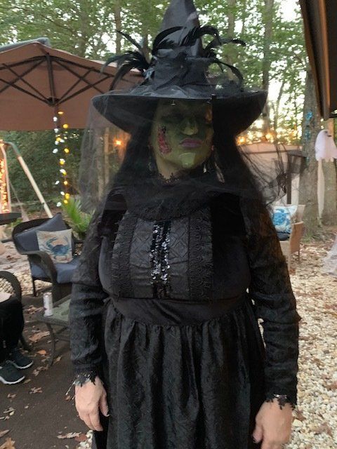 A woman in a witch costume is standing in front of an umbrella.