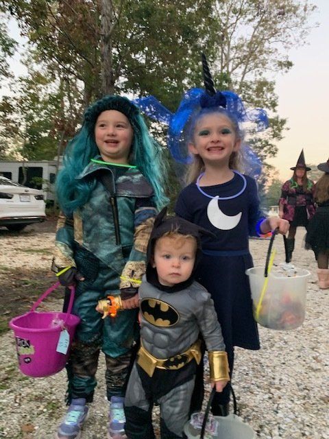 Three children in halloween costumes are posing for a picture