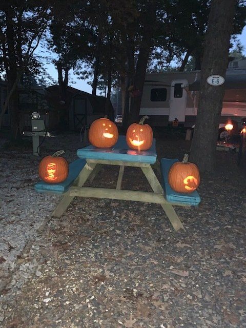A picnic table with three pumpkins carved into it