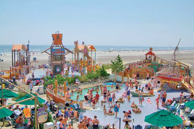 A large group of people are playing in a water park on the beach.