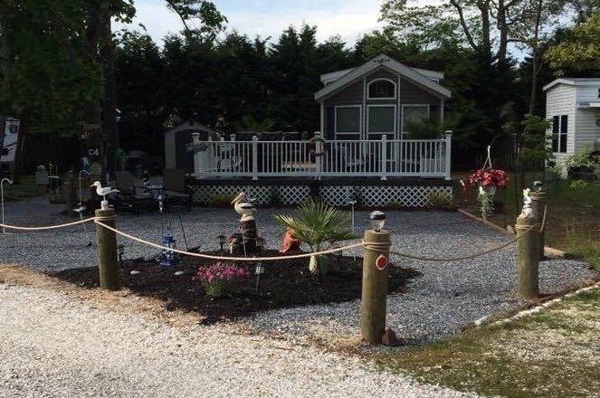 A mobile home with a deck and a rope fence in front of it.