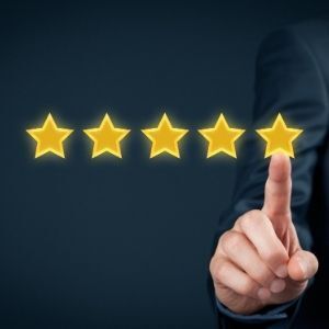 Hand of person in suit, pointing to glowing five-star rating.