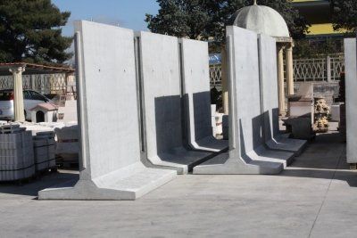 Sezioni e pannelli ad arco in cemento bianco disposti all'aperto su un lotto pavimentato.