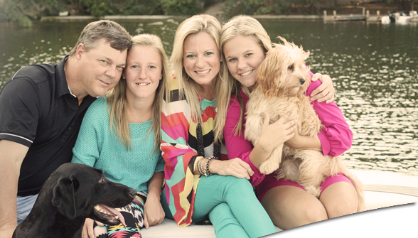 A family posing for a picture on a boat with a dog