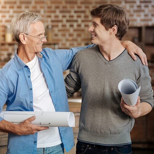 Two Contractors Review Blueprints At A Construction Site