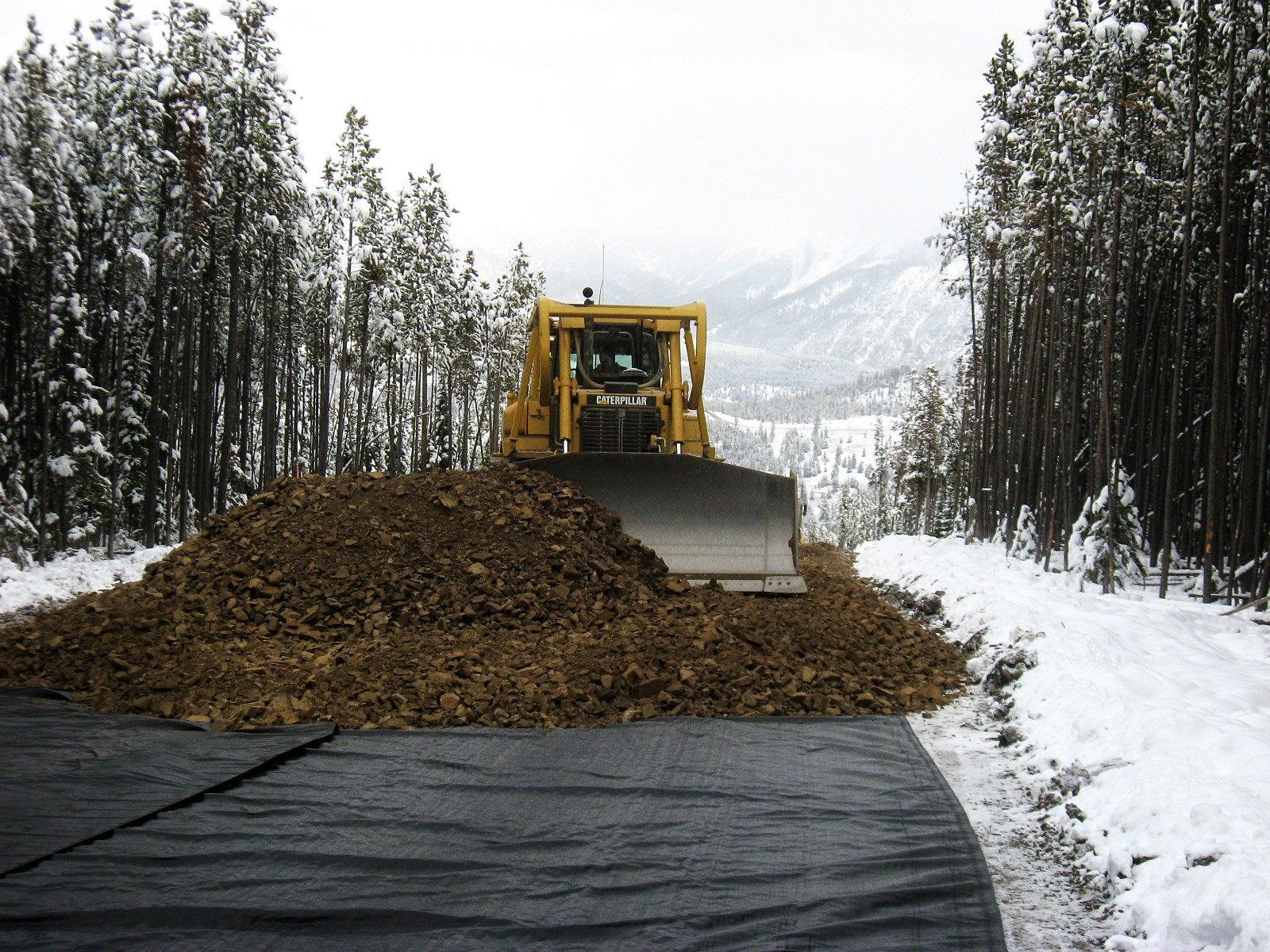 A bulldozer is driving down a snowy road