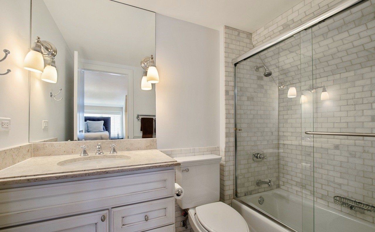 A bathroom with a sink , toilet , shower and mirror.