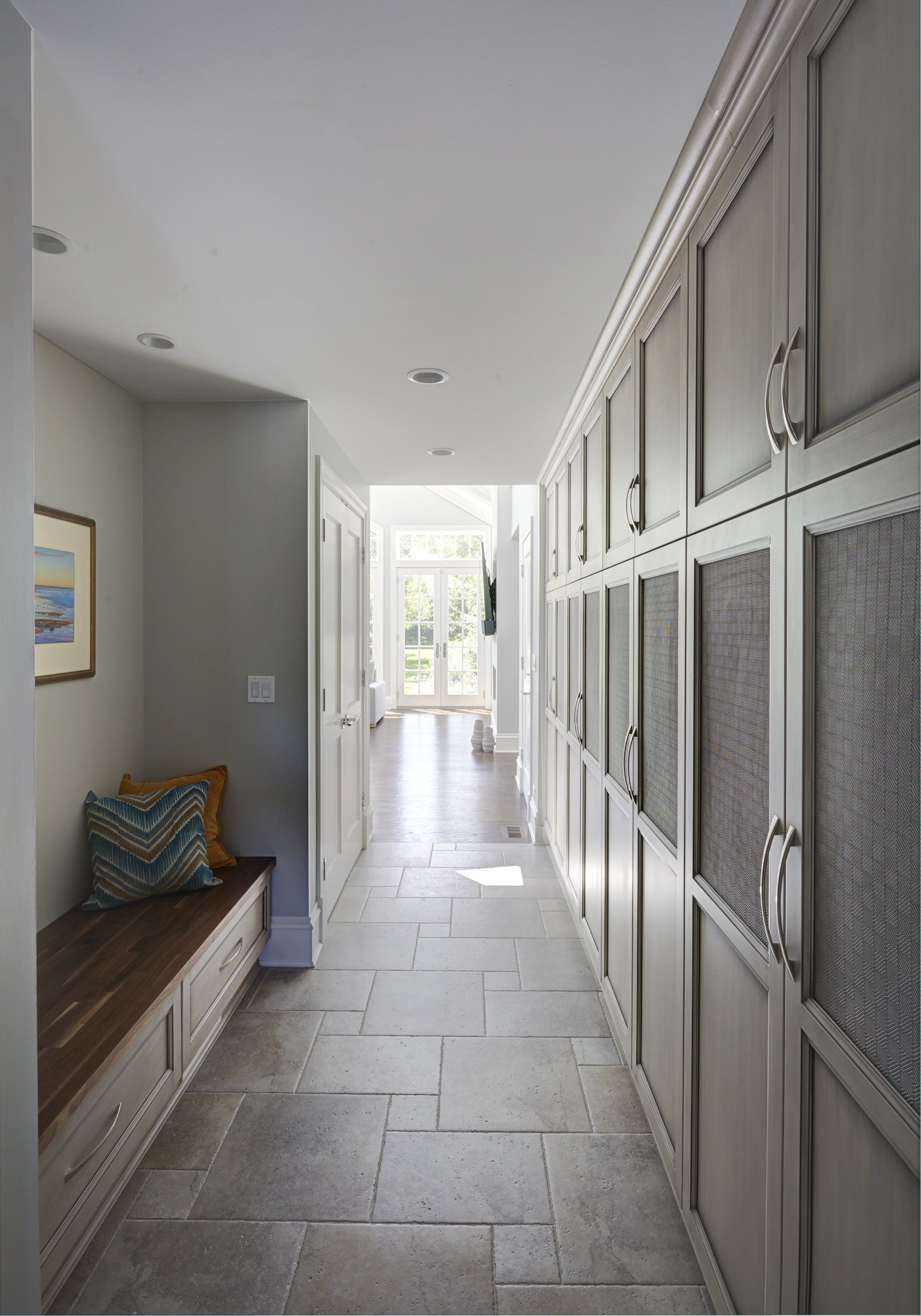 A long hallway with lots of cabinets and a bench