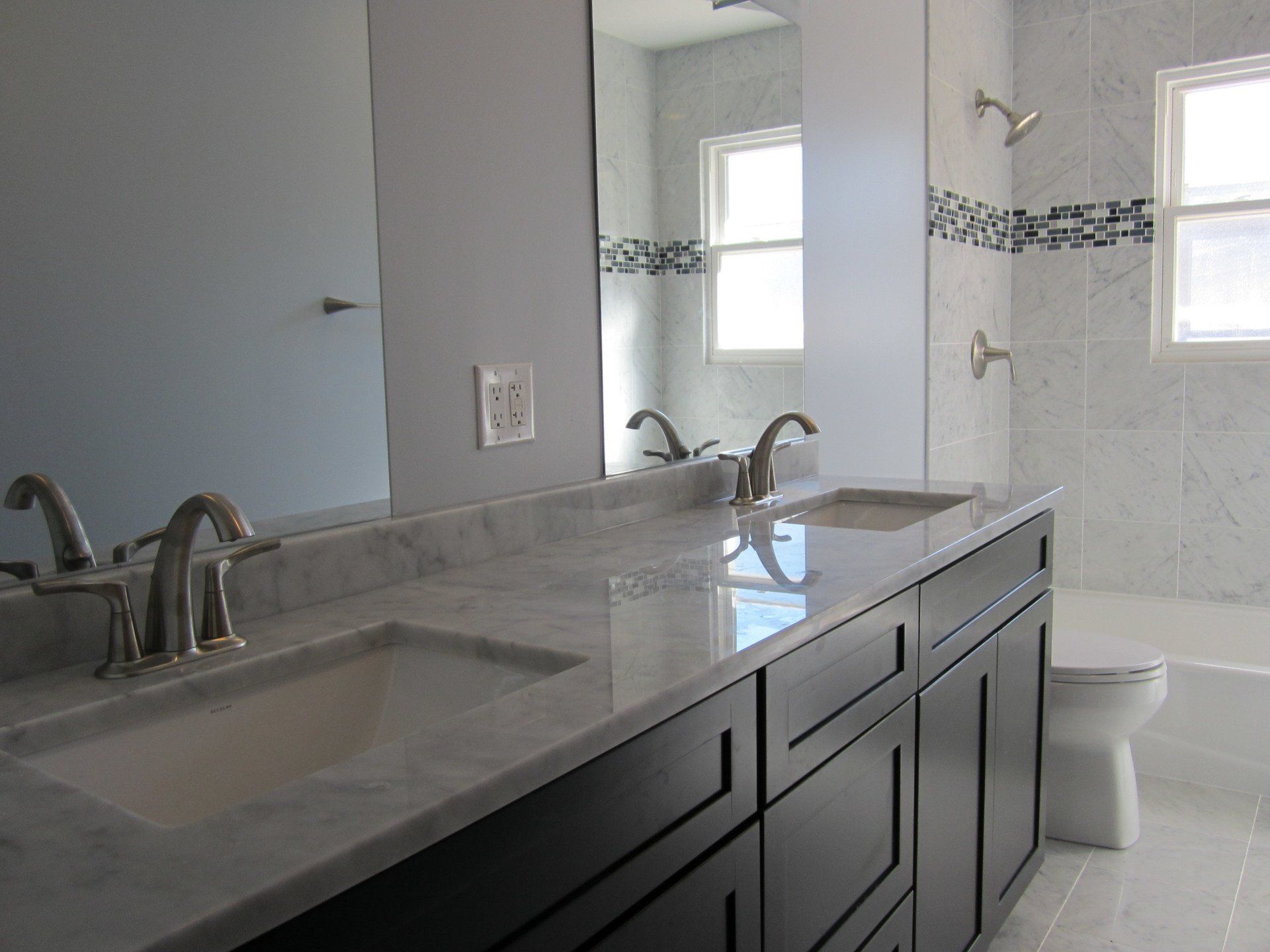 A bathroom with two sinks , a toilet , and a large mirror.