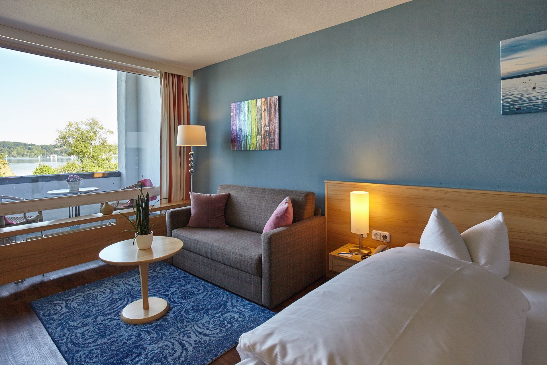 Gemütliches Zimmer mit Balkon, Seeblick, Doppelbett und klassischer Einrichtung.
