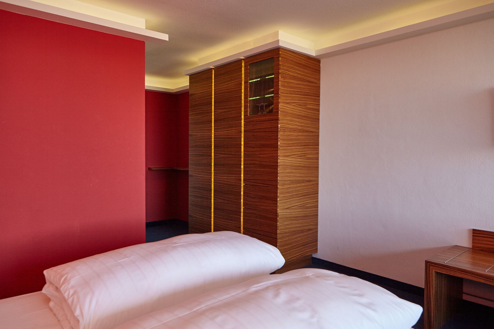 Ein Hotelzimmer mit zwei Betten, einem Schreibtisch und einem Kleiderschrank.