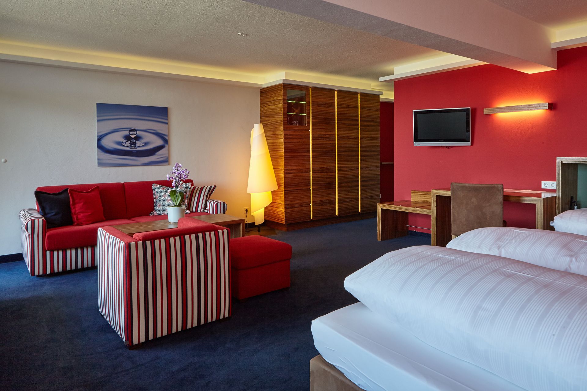 Großes Doppelzimmer mit roter Wand, Sitzbereich und eleganter Ausstattung.