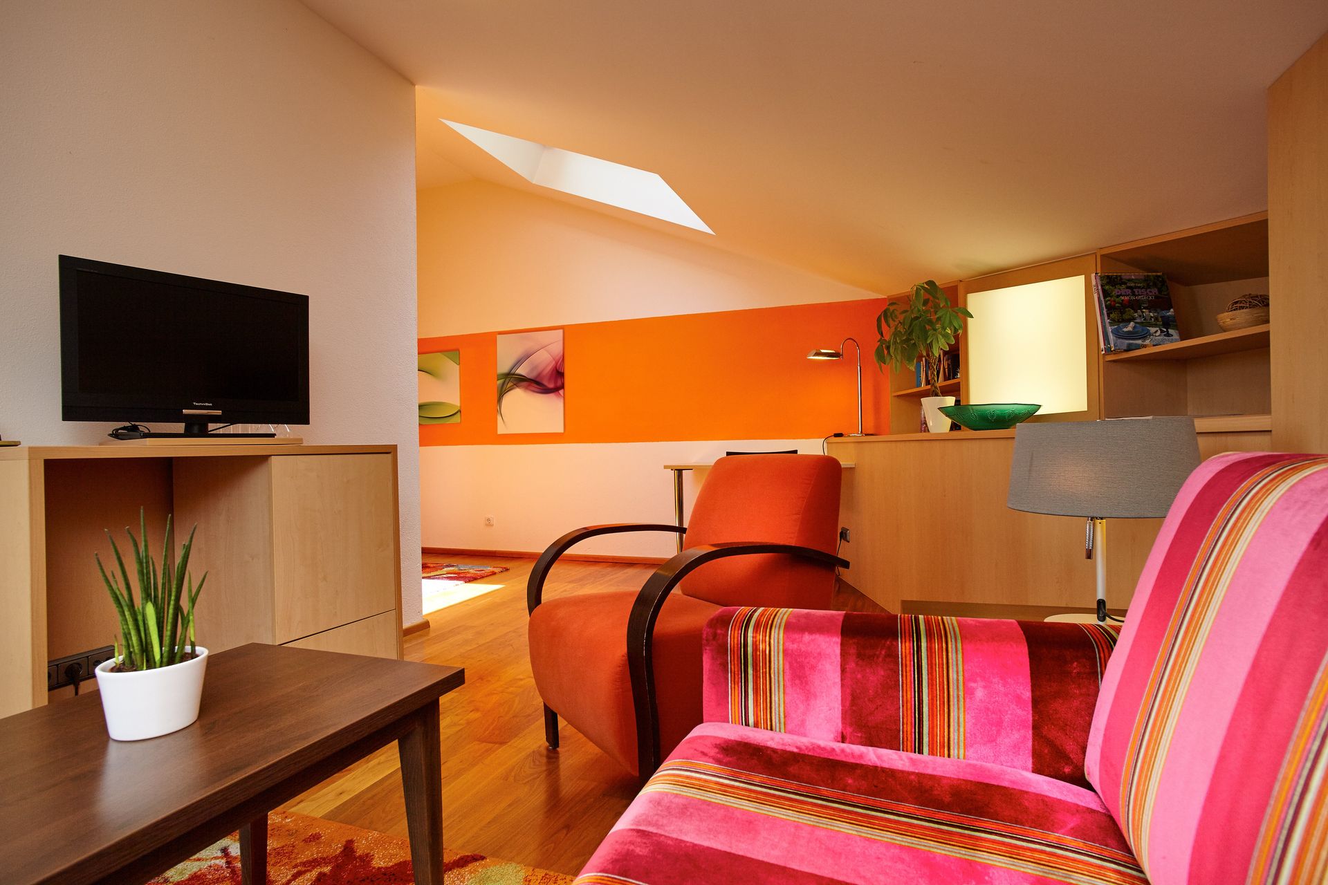 Ein Wohnzimmer mit einem Sofa, einem Sessel und einem Flachbildfernseher