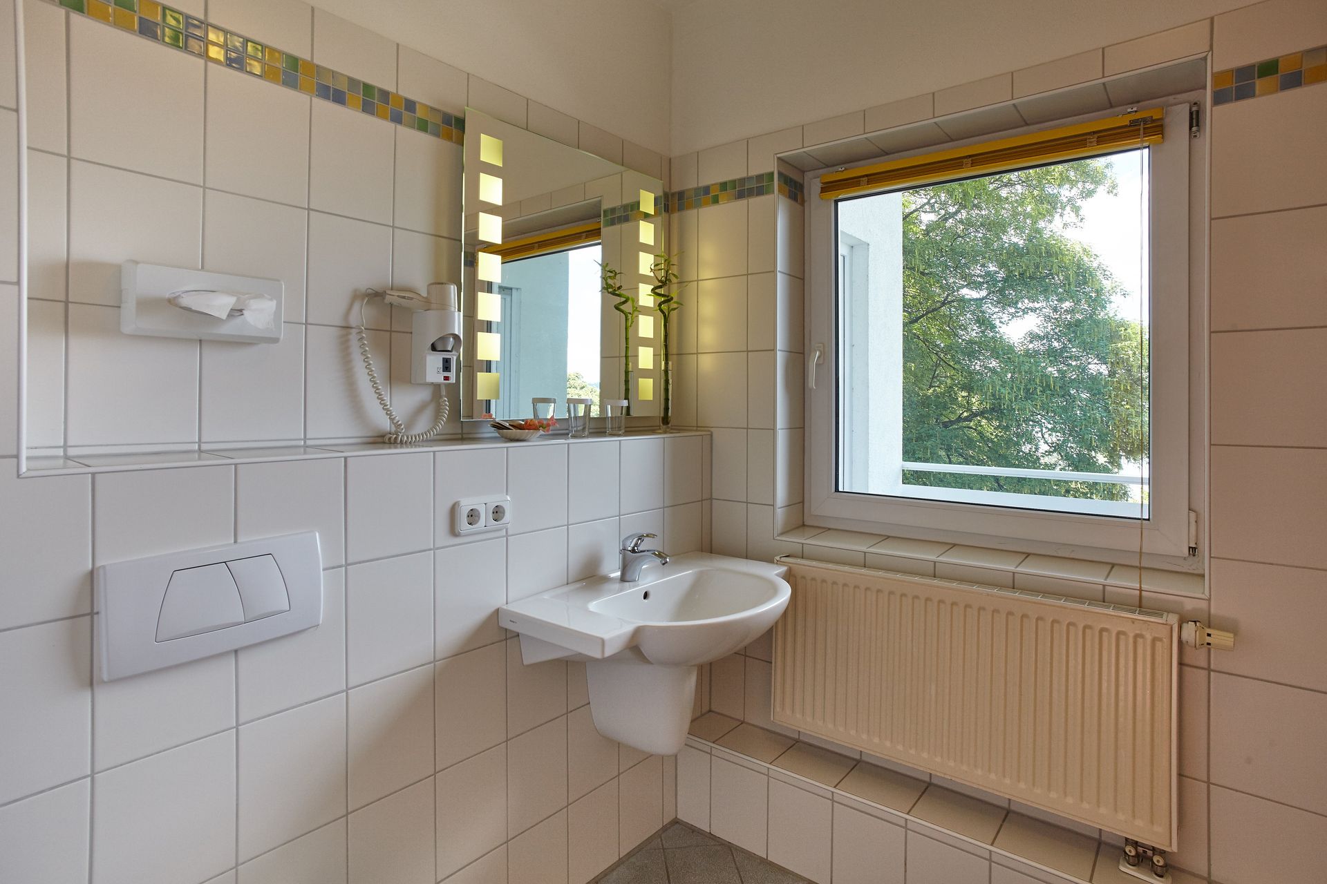 Modernes Badezimmer mit hellen Fliesen und Fenster im Hotel Schloss Berg.