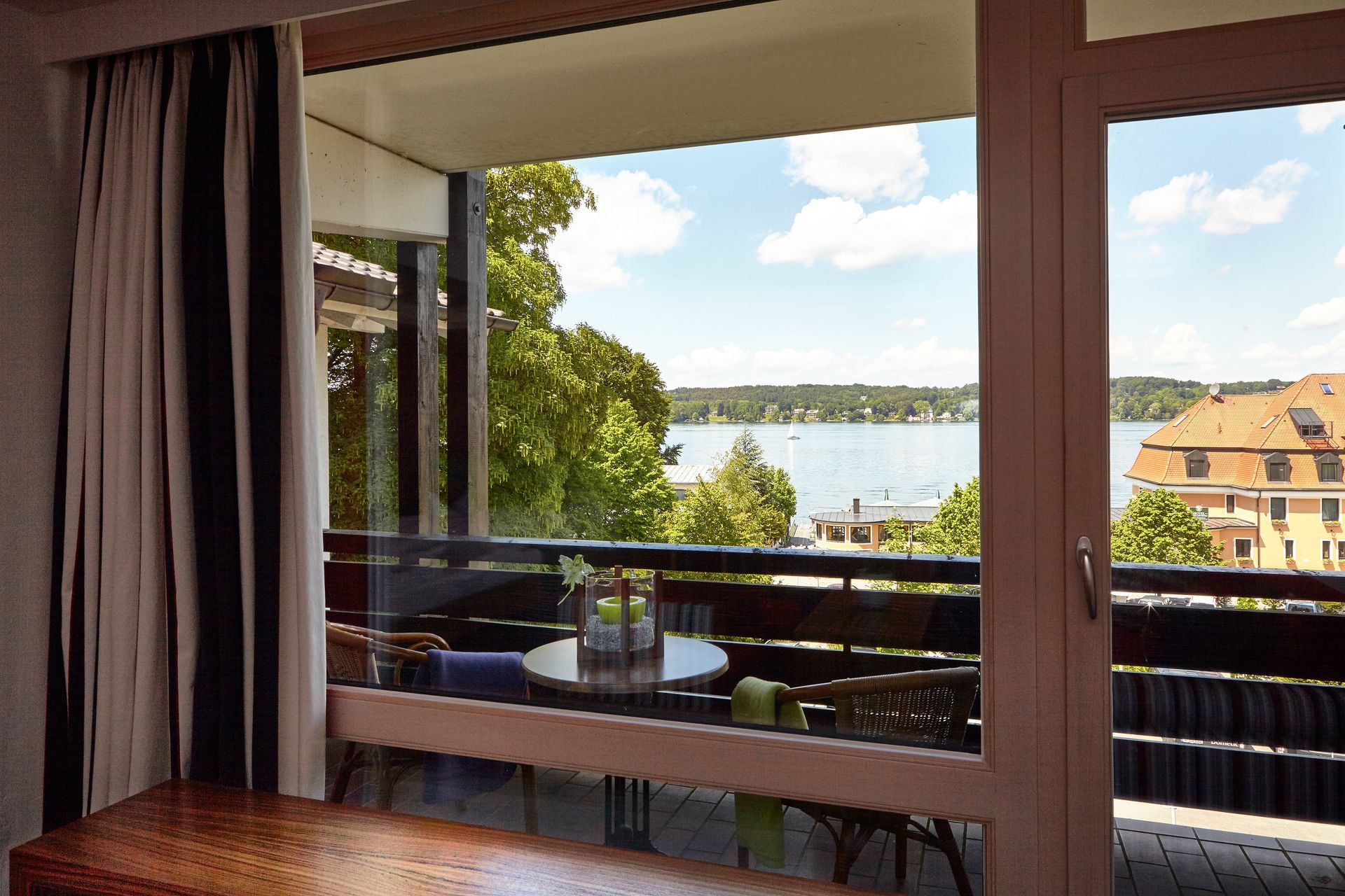 Balkon mit Tisch und Stühlen und Blick auf den Starnberger See.