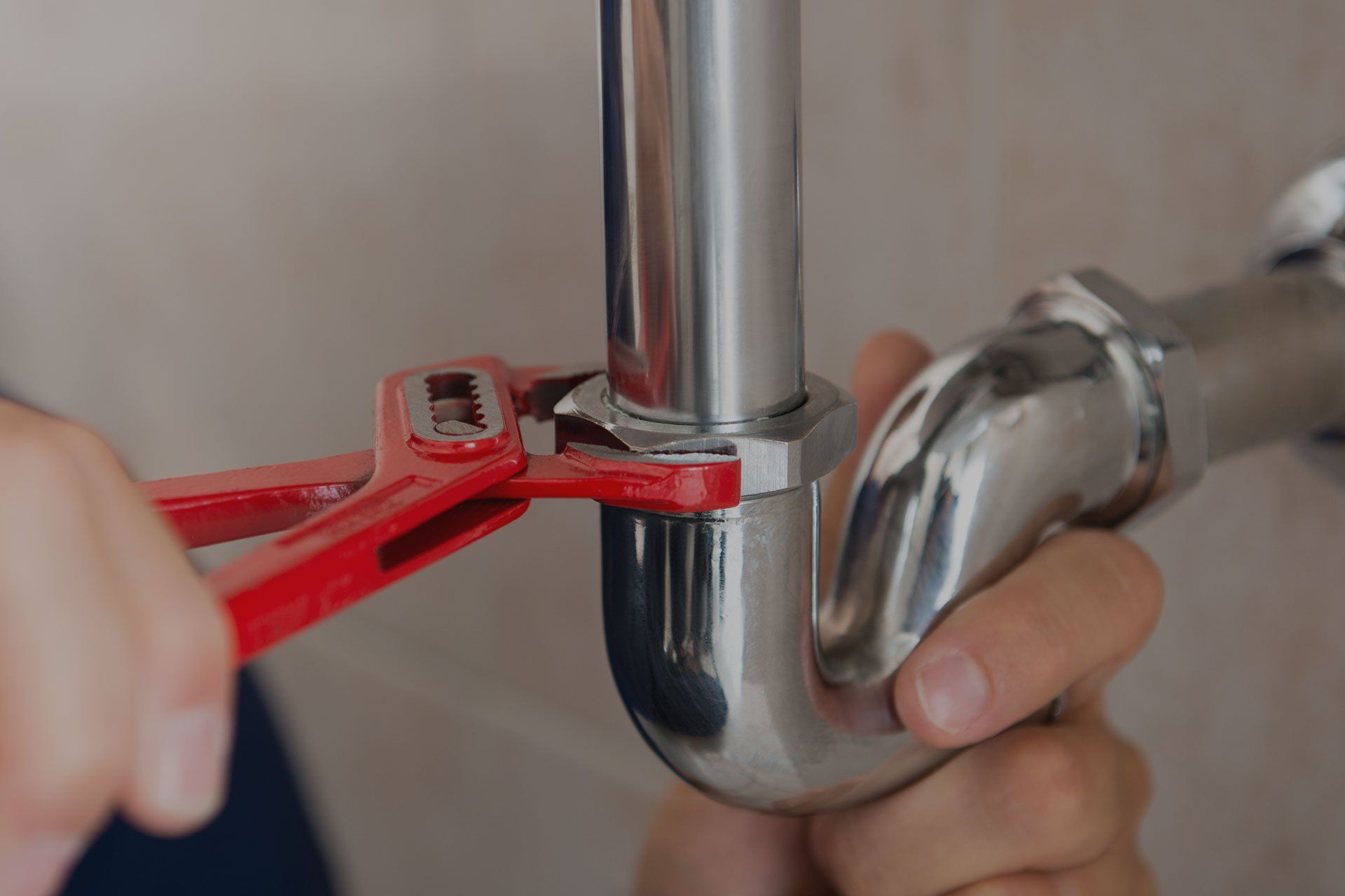 plumber tightening pipe under sink