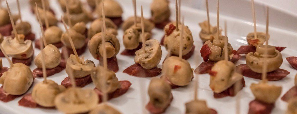 a white plate topped with appetizers on toothpicks .