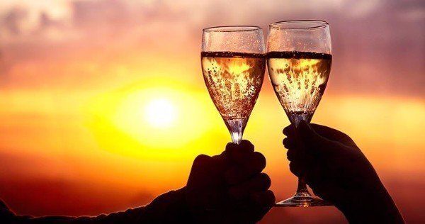 two people are toasting with champagne glasses at sunset .