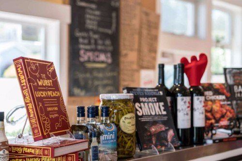 a shelf with bottles of wine , pickles , and a book on it .