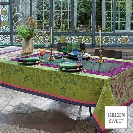 a table with plates , candles , and a green and purple tablecloth .