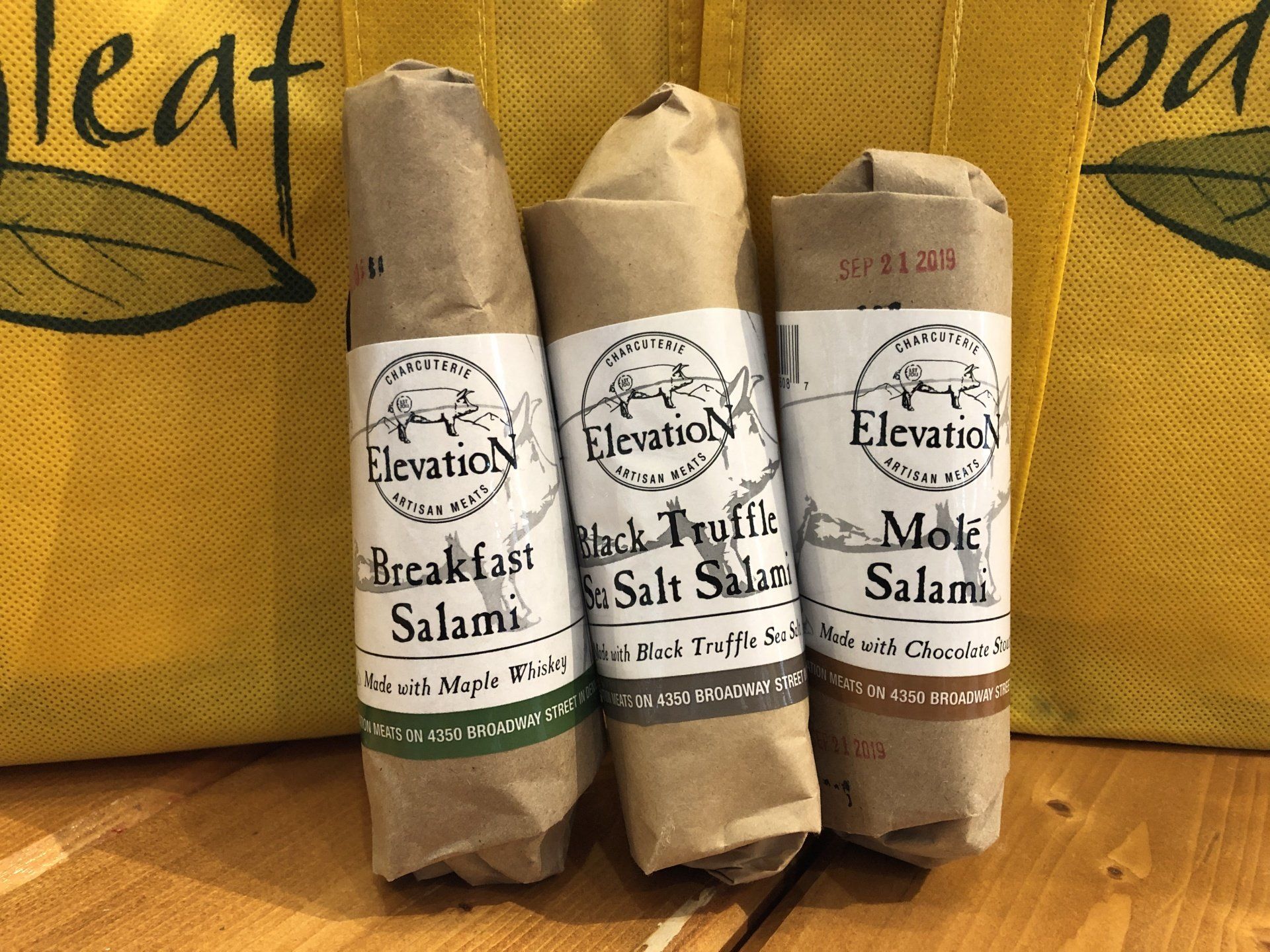 three rolls of breakfast salami are sitting on a wooden table .