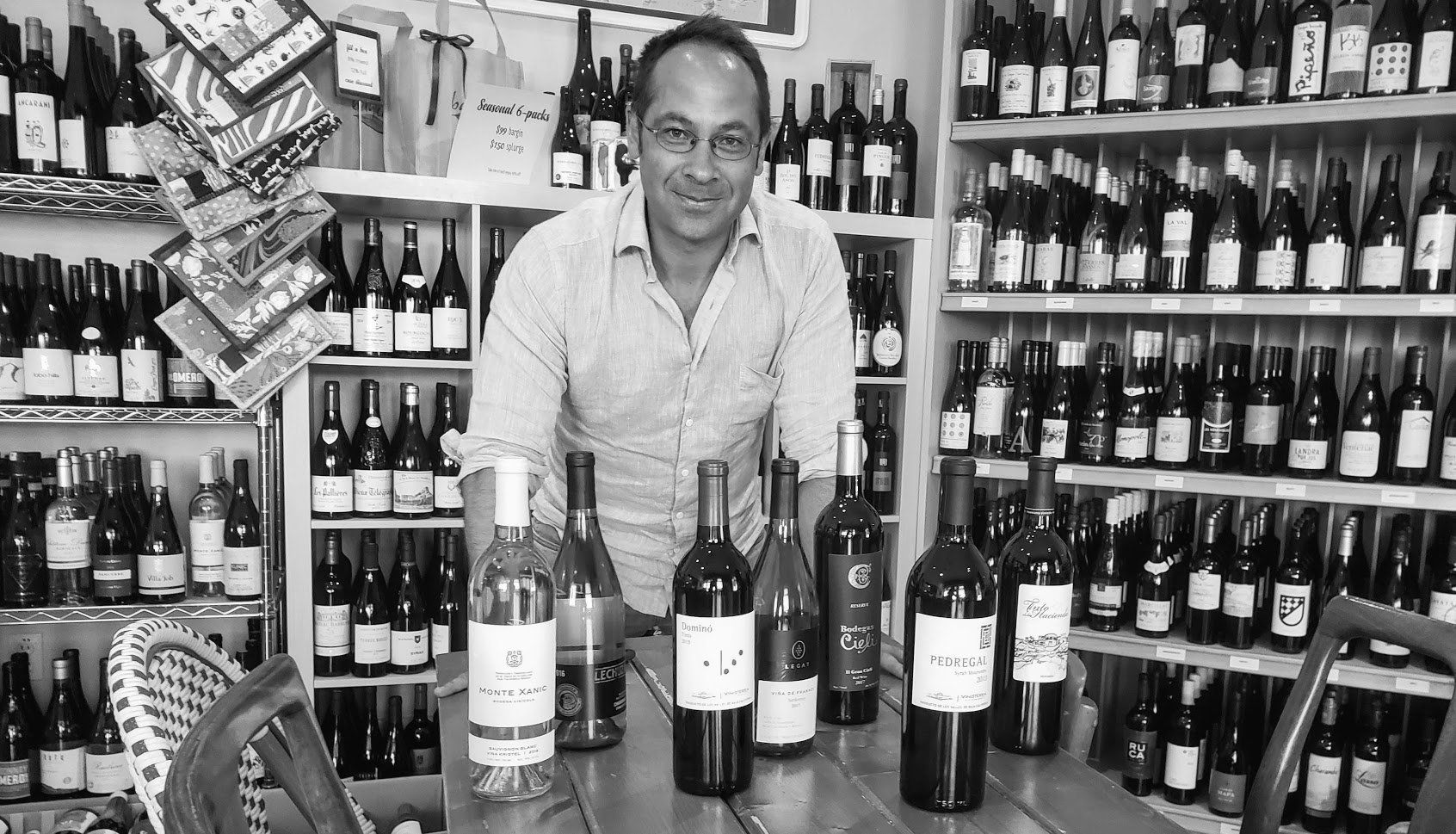 a man is standing in front of a table with bottles of wine on it .