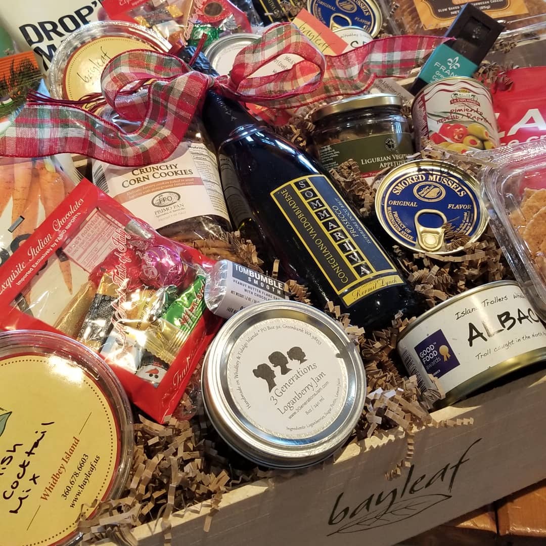 a box filled with a variety of food items including a bottle of extra virgin olive oil .